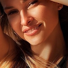 Smiling woman outdoors with sun-kissed skin.