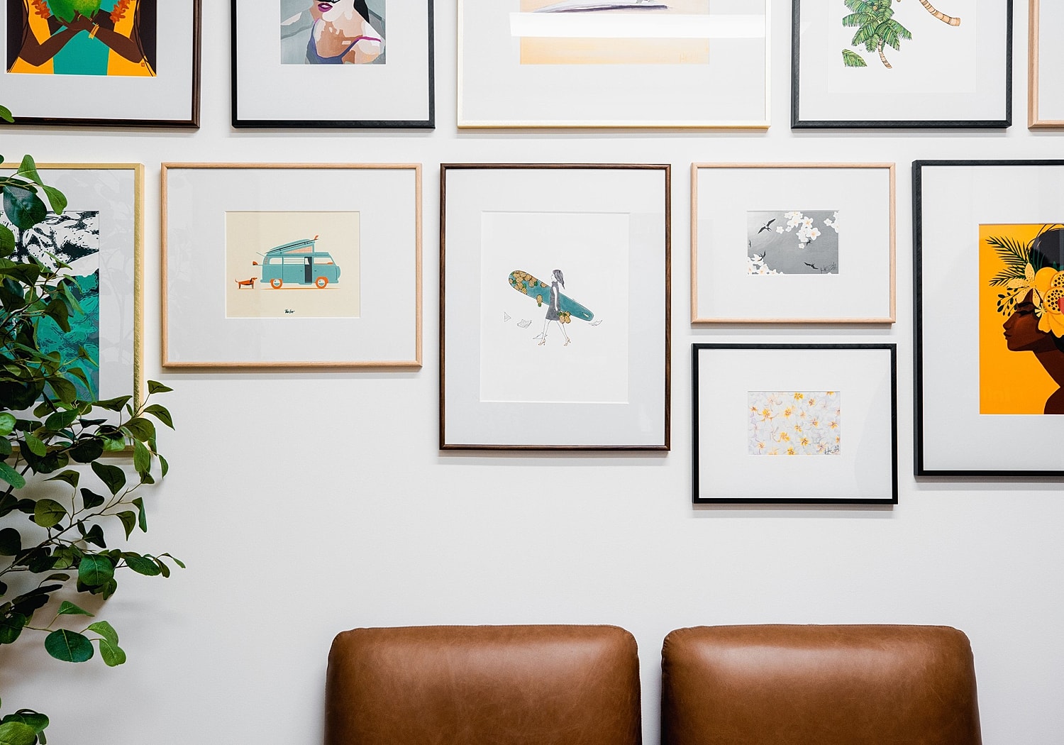 Gallery wall with various framed artworks and plants.