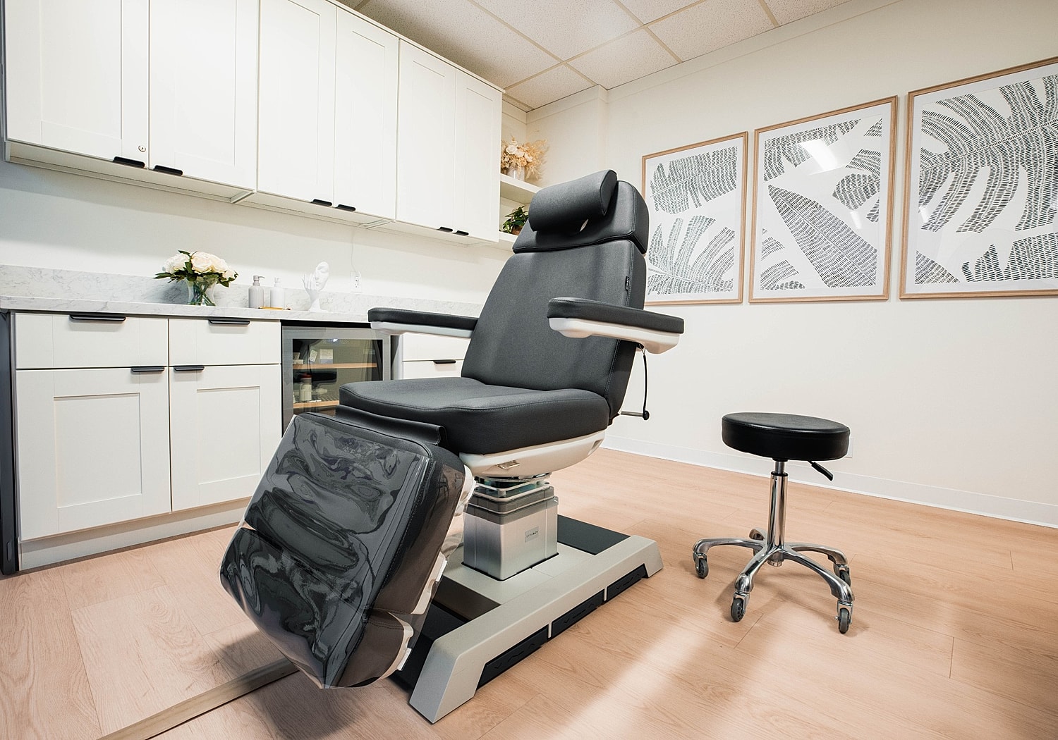 Cosmetic treatment room with reclining chair and stool.