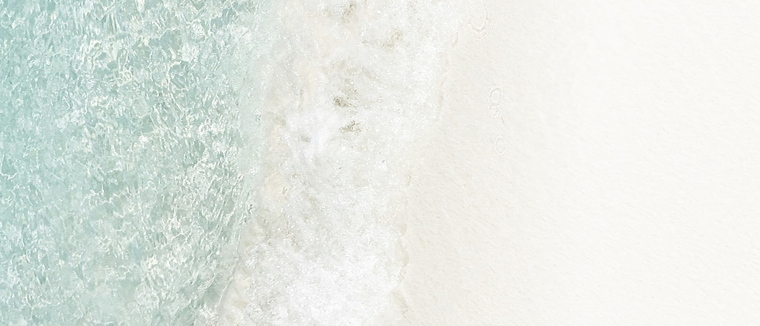 Gentle waves meeting soft white sand shoreline.