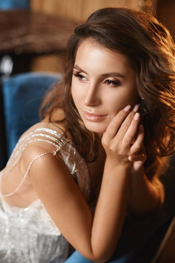Woman with wavy hair, posing elegantly indoors.