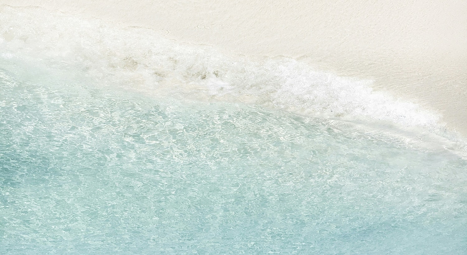 Clear turquoise water meets sandy shoreline.