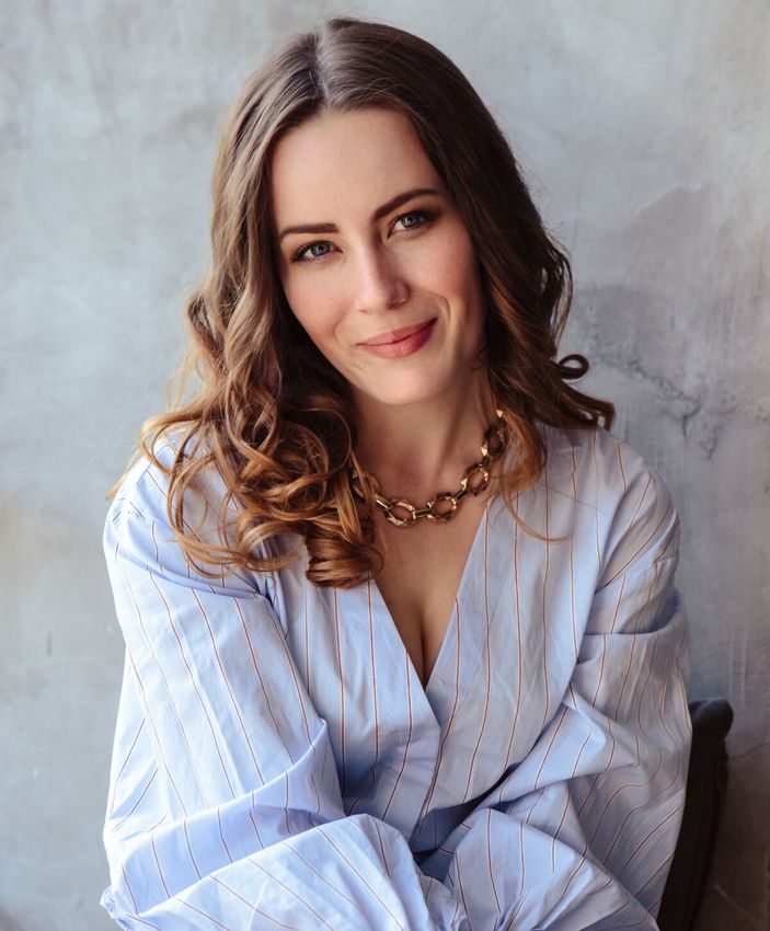 Smiling woman with long, wavy hair and necklace.
