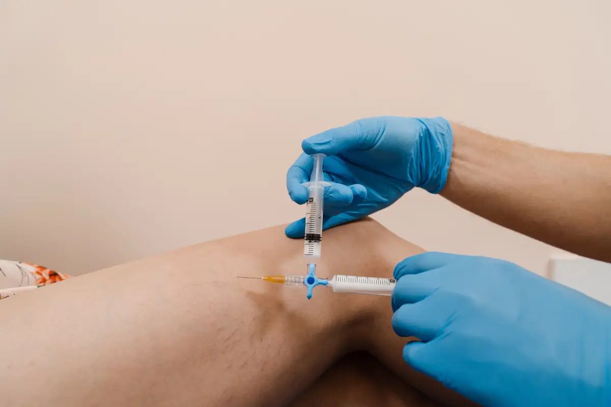 Syringe injection into a patient's knee joint.